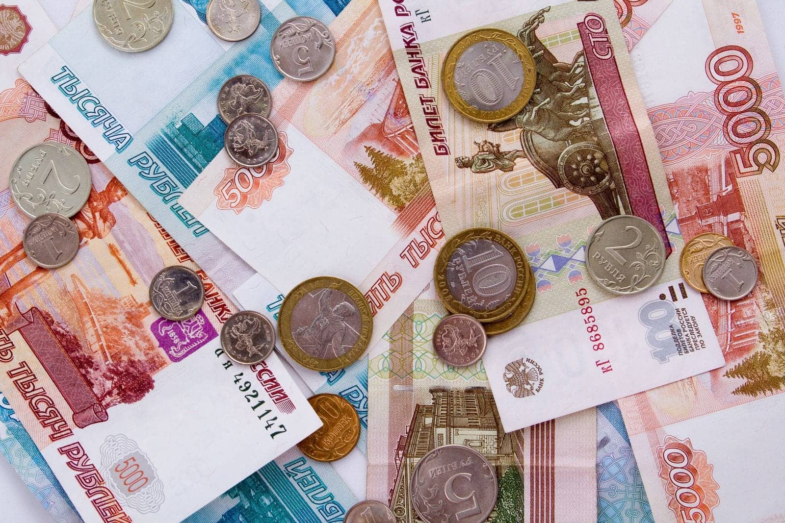 Российские банкноты по 1000 и 5000 рублей с рассыпанными монетами